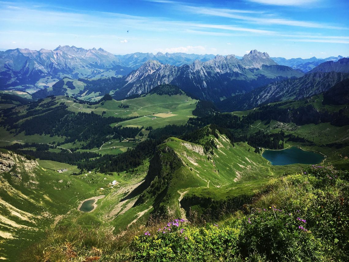 Vue plongeante sur un lac d'altitude et les sommets verdoyants des Alpes lors d'une retraite de ressourcement - Bas les masques